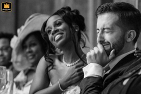 At Fawsley Hall, Northamptonshire, the bride and groom share an emotional reaction during the best man's heartfelt speech. Captured in black and white, their faces reveal genuine love, gratitude, and deep connection in the moment.